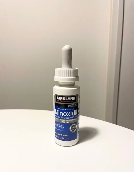 机の上に置いたカークランド ミノキシジル(KIRKLAND Minoxidil)のボトル